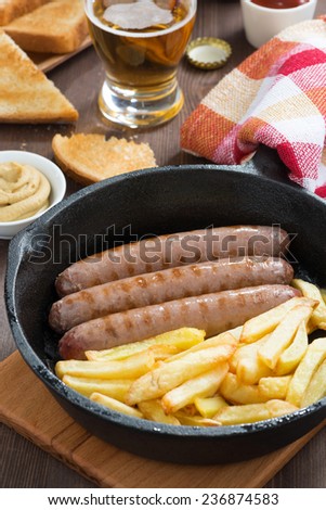 grilled sausages with French fries, toast and beer, close-up