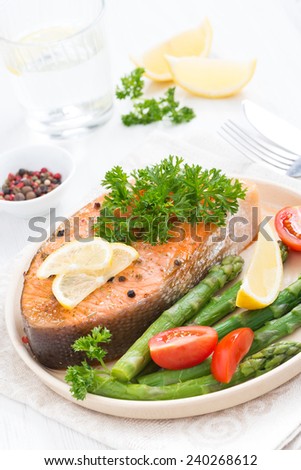 baked salmon with asparagus, parsley and lemon, top view, vertical