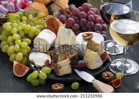 soft delicacy cheeses and snacks for wine on a dark background, close-up