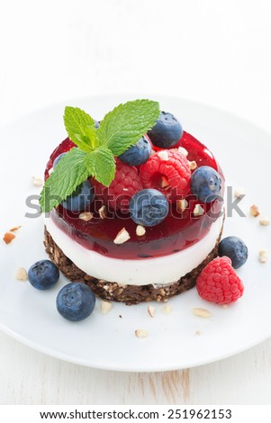 delicious cake with fruit jelly and fresh berries on a white plate, top view, vertical