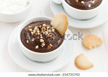 chocolate mousse with biscuits and nuts in white cups, top view, horizontal