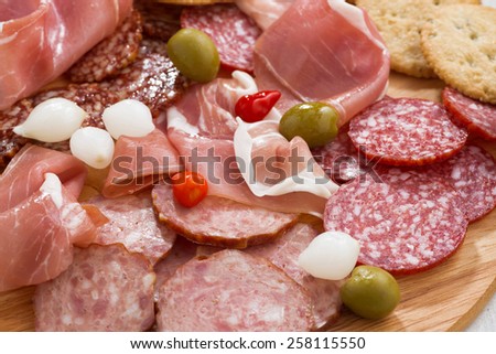 Assorted deli meat snacks, sausages and pickles on board, close-up, horizontal
