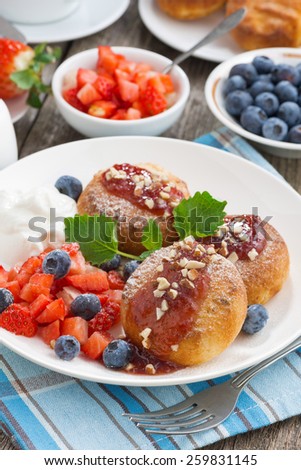 sweet cheese pancakes with berries and cream on a plate, close-up, vertical