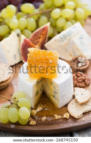 camembert with honey and fruit close-up on a wooden tray, vertical, close-up, top view