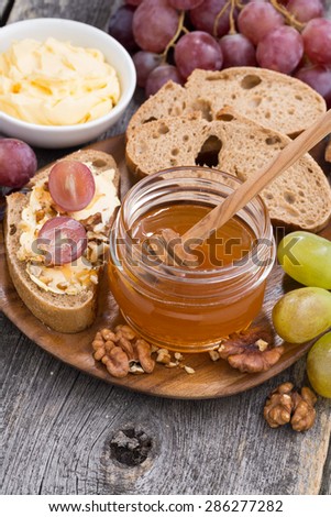 flavored honey, bread with butter and grape on wooden board, vertical, top view