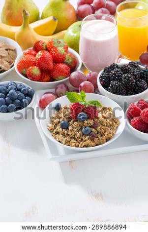 Delicious and healthy breakfast with fruits, berries and cereal on white table, vertical, top view