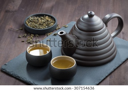 freshly brewed green tea in ceramic ware on wooden table, horizontal