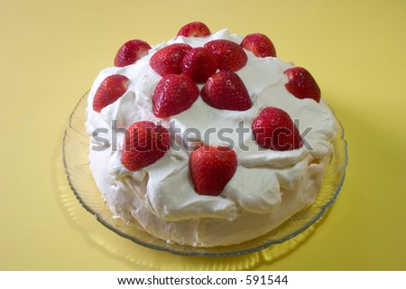 A pavlova desert with whipped cream and fresh strawberries on top