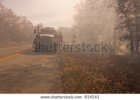 A fire tender parked by the highway while the crew fight a bush fire near by