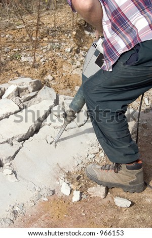 A man breaking up concrete with a jack hammer