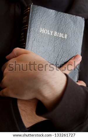 Young man holding a Bible closely