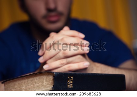 Young man praying on Bible