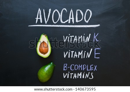 avocado on a black background, an inscription on a blackboard with the indication of the vitamins containing in avocado