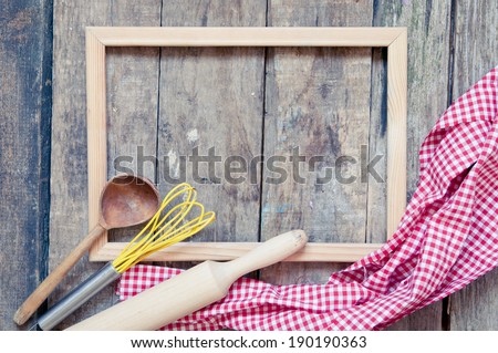 Retro kitchen utensils and vintage frame on wooden background