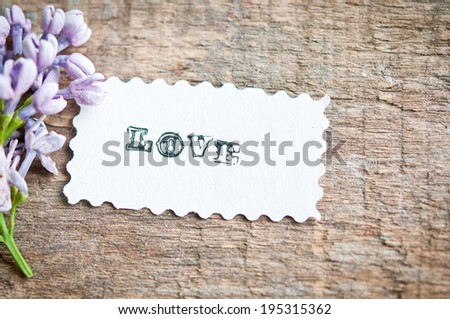 lilac flowers on wooden background. card with sample text Love