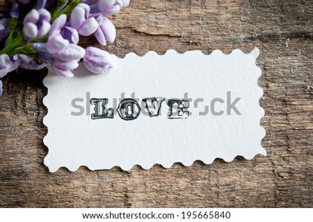 lilac flowers on wooden background. card with sample text Love