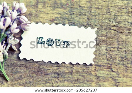 Lilac flowers on wooden background. card with sample text Love/retro filter effect