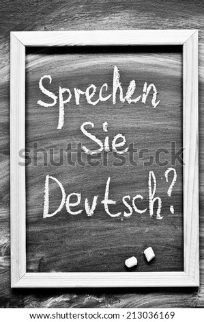 Sprechen Sie Deutsch? Do you speak German question handwritten with white chalk on a blackboard