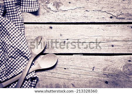 Serving spoons on checkered cloth lying on wooden surface