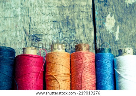 Vintage Background with colorful bobbins with thread  on the old wooden background/retro filter