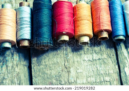 Vintage Background with colorful bobbins with thread  on the old wooden background/retro filter
