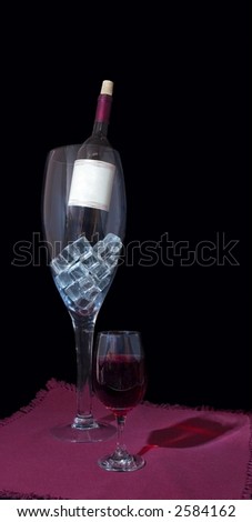 Large wine glass containing wine bottle and ice and small wine glass full of wine on napkin and black background. Small wine glass casting \