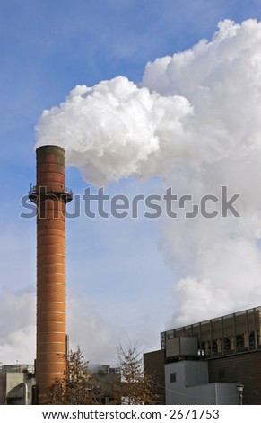 Smokestack sends up white smoke against wispy clouded blue sky