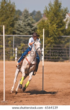 Tween the Poles - Equestrian Games - cowgirl and her horse make their way through last two poles during pole-weaving competition - stock photo