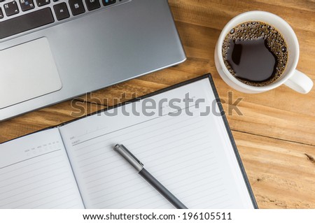 Laptop with coffee cup, notebook and pen on wooden background, concept for home office
