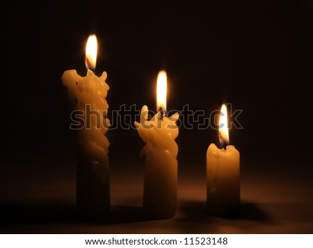 Three burning candles in dark