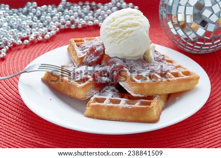 freshly baked Belgian waffles with ice cream and strawberry jam in a white plate on a red table with a  mirror balls