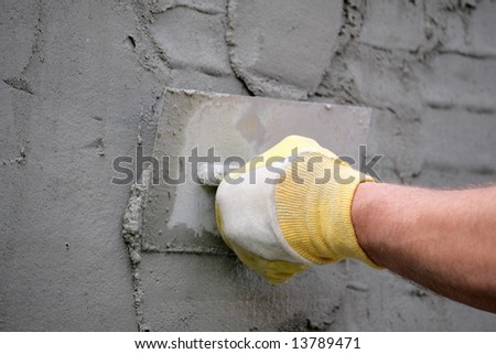 Hand with plastering tool apply plaster