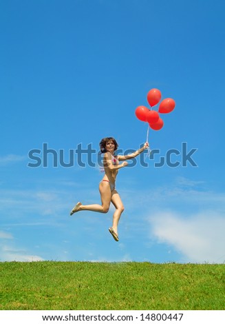 Beautiful lady in bikini with red balls jumping