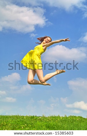 Young lady in yellow dress  jumping on the background of the sky