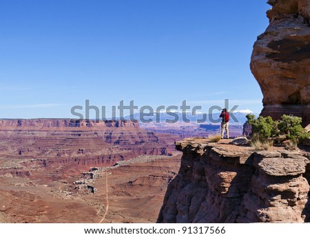 Lone hiker looks over Canyon Lands valley and Mesa in Utah