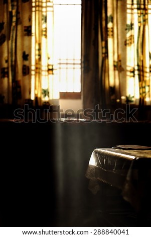 Morning light peeping into the room through a curtain, an image captured against light with some smoke filled in room to create a soft focus effect