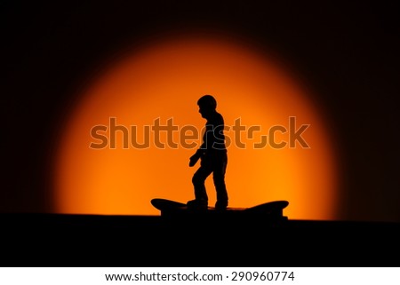 Silhouette of a toy girl on a skate board shot in studio