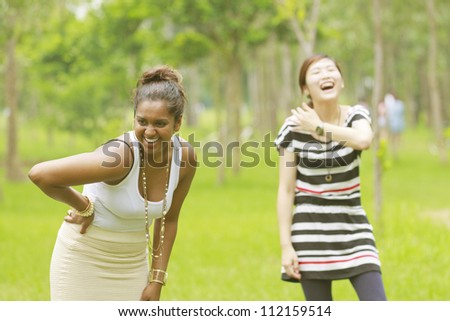 Two different races woman laughing, black and asian.