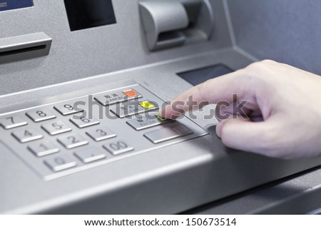 Human hand touching ATM machine