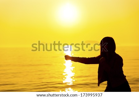 Silhouette of the boxing girl exercising at sunset
