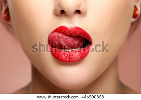 Close-up view of woman licking red lips