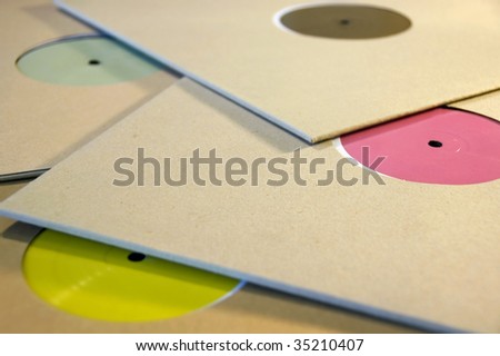 Pile of cardboard sleeve vinyl music records with colorful blank labels.