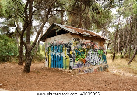 Graffiti covered cinder block hut in a forest.