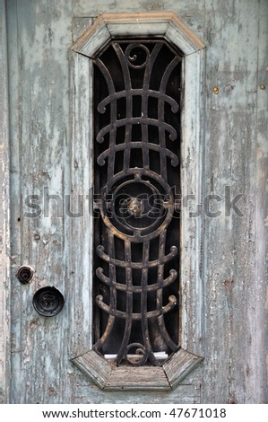 Weathered wooden door with peeling paint and vintage metalwork pattern.