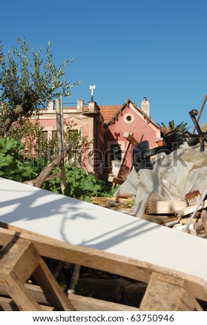 Pile of broken furniture and debris in the abandoned neoclassical house garden.