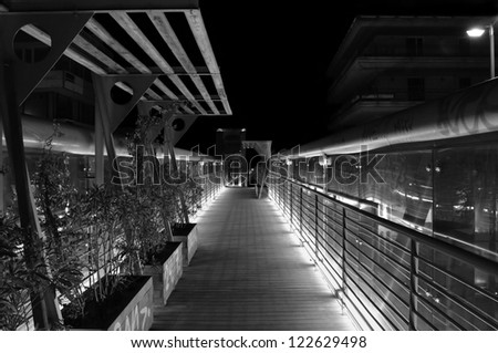 Pedestrian overpass metal bridge above the motorway at night. Black and white.