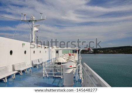 Ship deck with benches, portholes and inflatable life-rafts. Sea and sky horizon travel background.