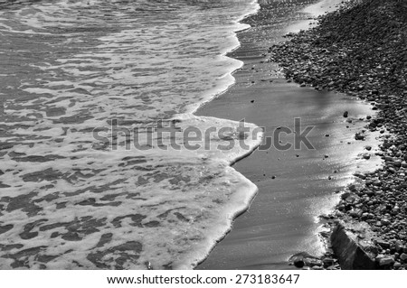 Waves on stone beach waters edge abstract sea background. Black and white.