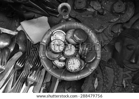ATHENS, GREECE - JUNE 12, 2015: Antique pocket watches and other vintage objects for sale at street market. Black and white.