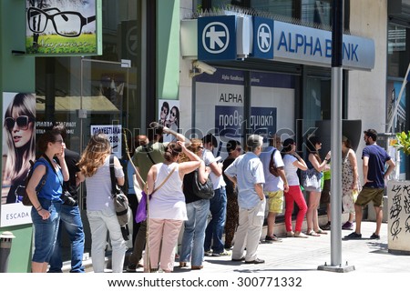 ATHENS, GREECE - JULY 1, 2015: Long line of people waiting to withdraw cash money from ATM cashpoint outside a closed bank. Capital controls during greek financial crisis.